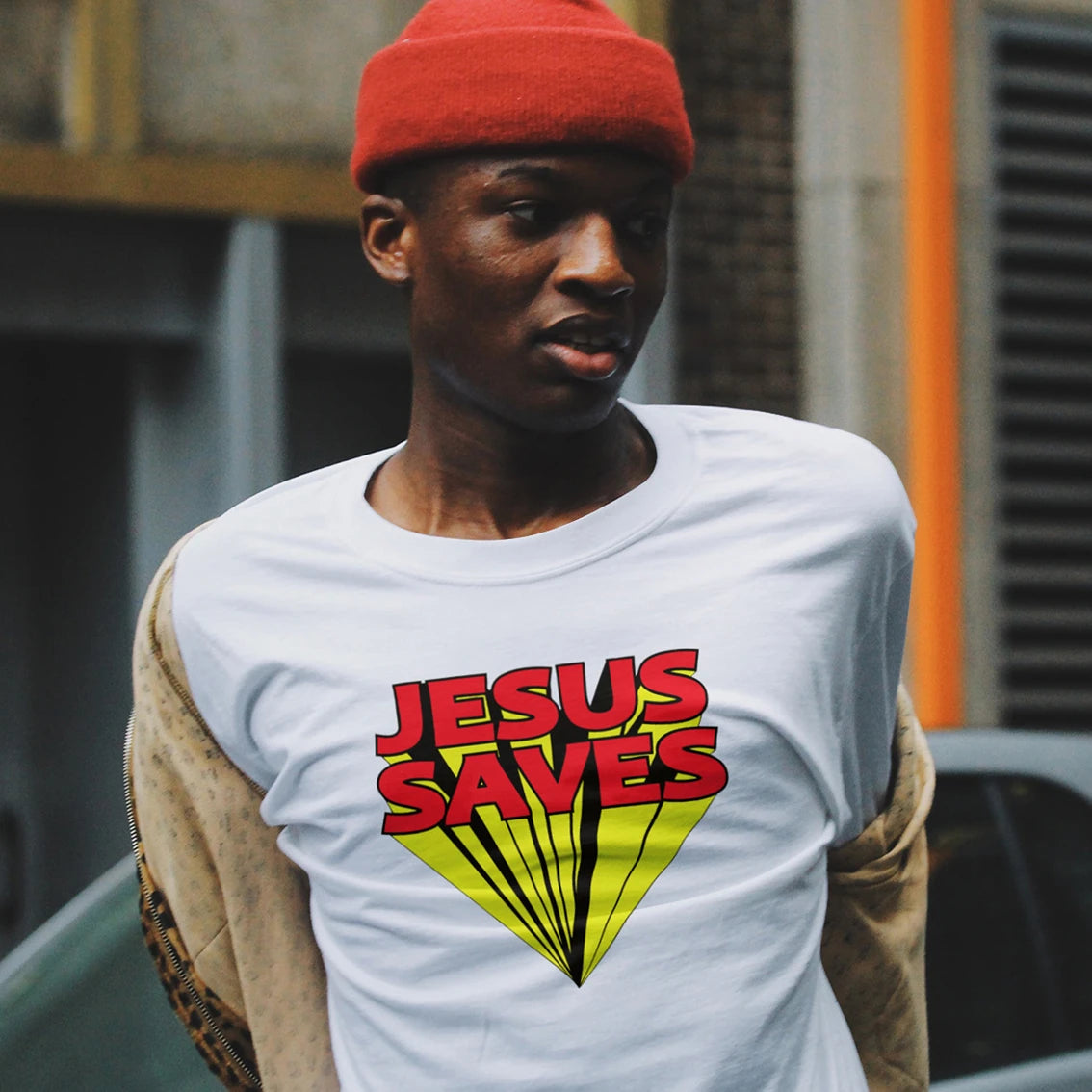 A man is wearing a white t-shirt with 'Jesus Saves' graphic design outdoors.