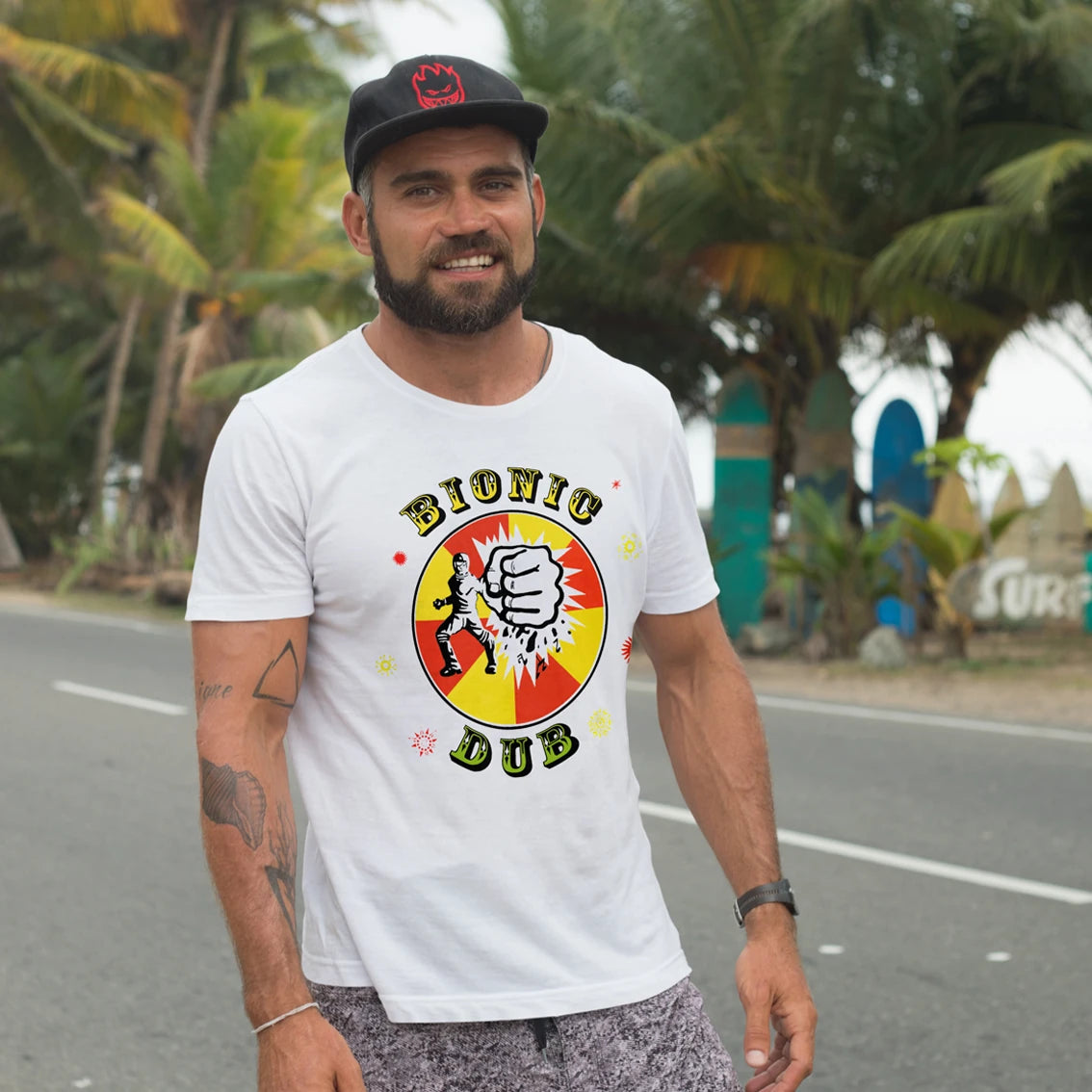 Man wearing a white t-shirt with 'Bionic Dub' graphic design outdoors.