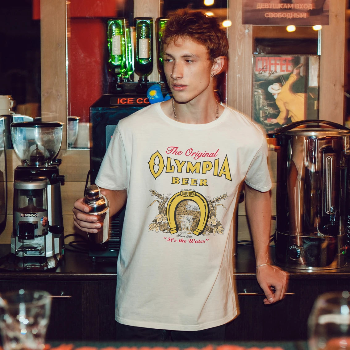 Man wearing an Olympia Beer t-shirt in a bar setting
