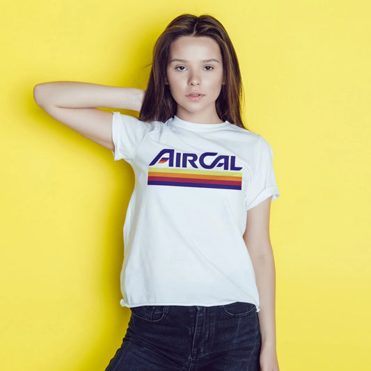 A young woman is wearing a white t-shirt with 'AIRCAL' text and colourful stripey design on a yellow background