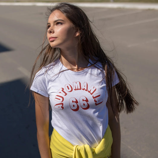 A woman wearing a white t-shirt with red and white text saying 'Automania 66' standing on a road