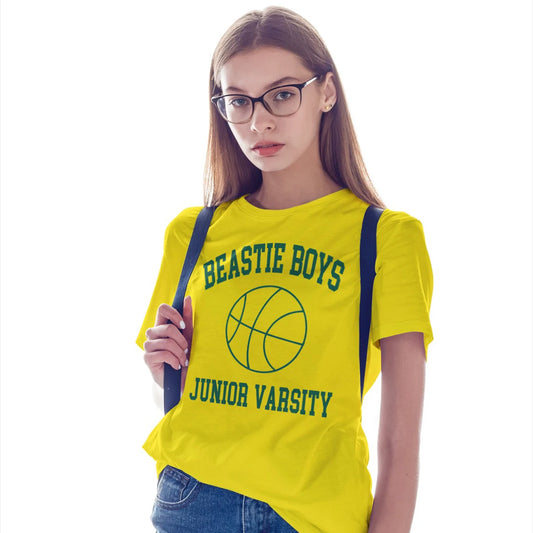 A woman in glasses is wearing a yellow t-shirt with 'BEASTIE BOYS JUNIOR VARSITY' text and a picture of the ball, on a white background