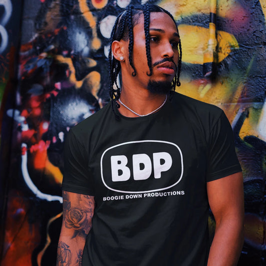 A man ia wearing a black t-shirt with 'BDP Boogie Down Productions' logo with a colorful graffiti wall background.