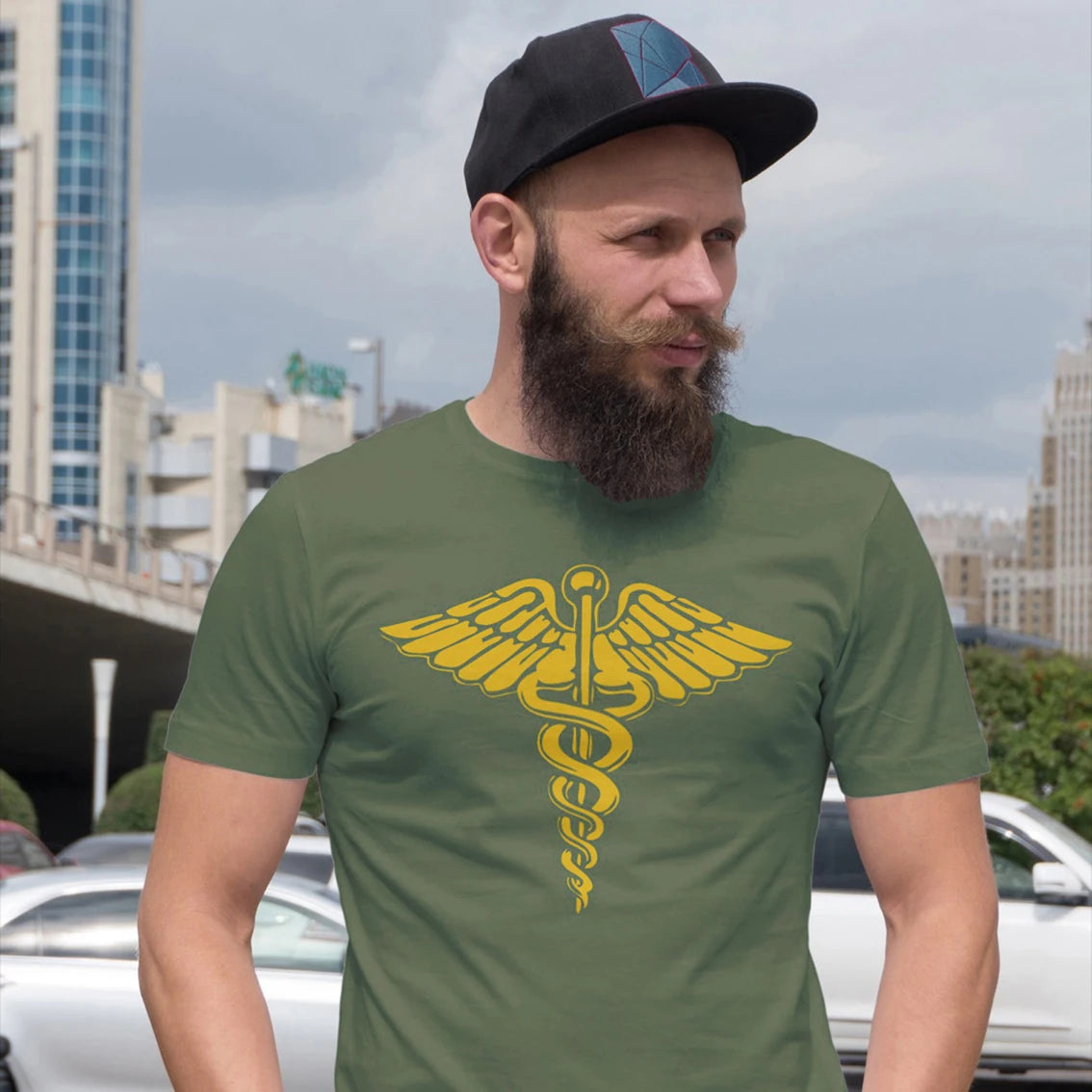 A man is wearing a green t-shirt with a yellow caduceus symbol in an urban setting