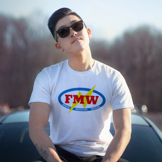 A man in sunglasses is wearing a white t-shirt with a colorful logo and 'FMW - Frontier, Martial Arts, Wrestling' text sitting outdoors on car bonnet.