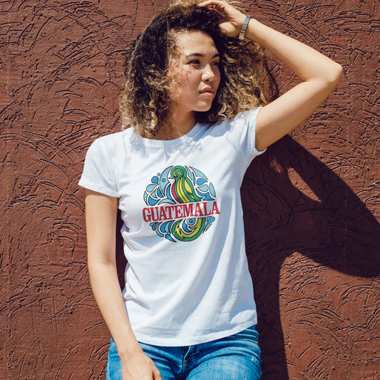 A woman is wearing a white t-shirt with 'Guatemala' red text on a colourful design with a bird against a textured brown wall