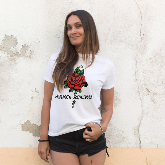 A woman is wearing a white t-shirt with a red rose and 'Hanoi Rocks' text against a textured wall.