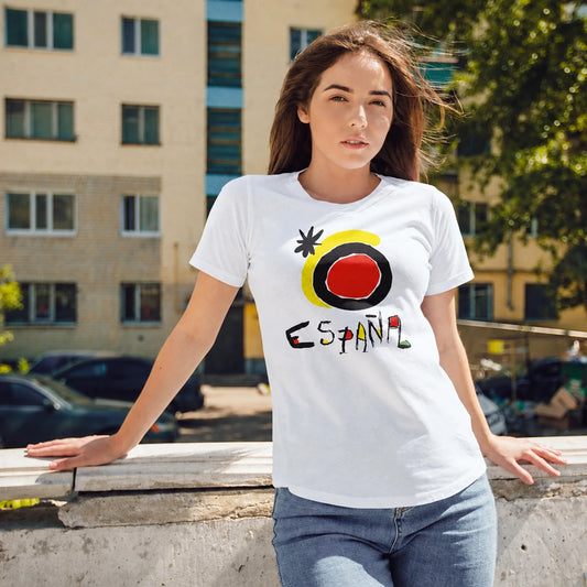 A woman is wearing a white t-shirt with a colorful sunshine design and 'ESPAÑA' text, standing outdoors against a background of buildings and trees.