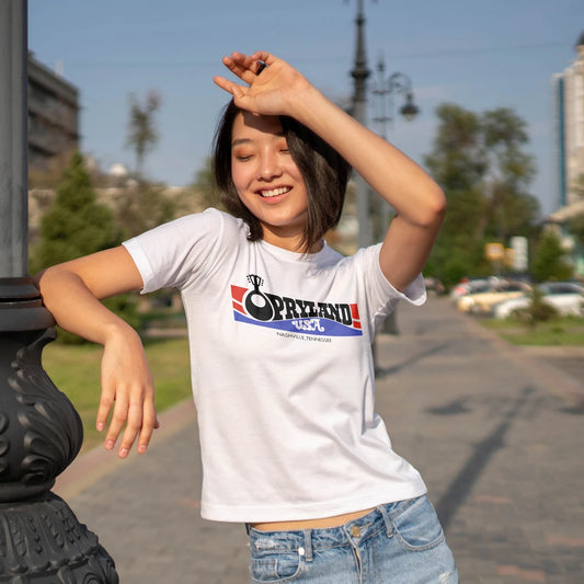 Woman wearing a white t-shirt with a 'Opryland USA' logo, standing outdoors on a sunny day.