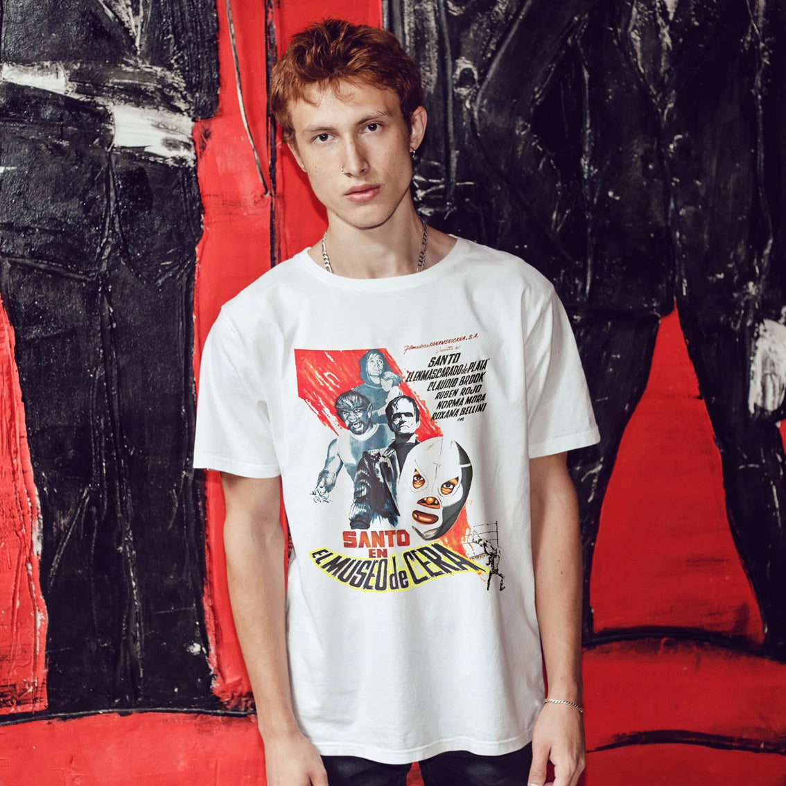 Man wearing a white t-shirt with graphic design  and 'Santo In The Wax Museum' text in front of a colorful abstract background