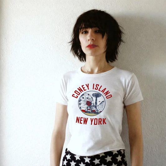 Woamn wearing a white t-shirt with 'Coney Island New York' design against a plain background