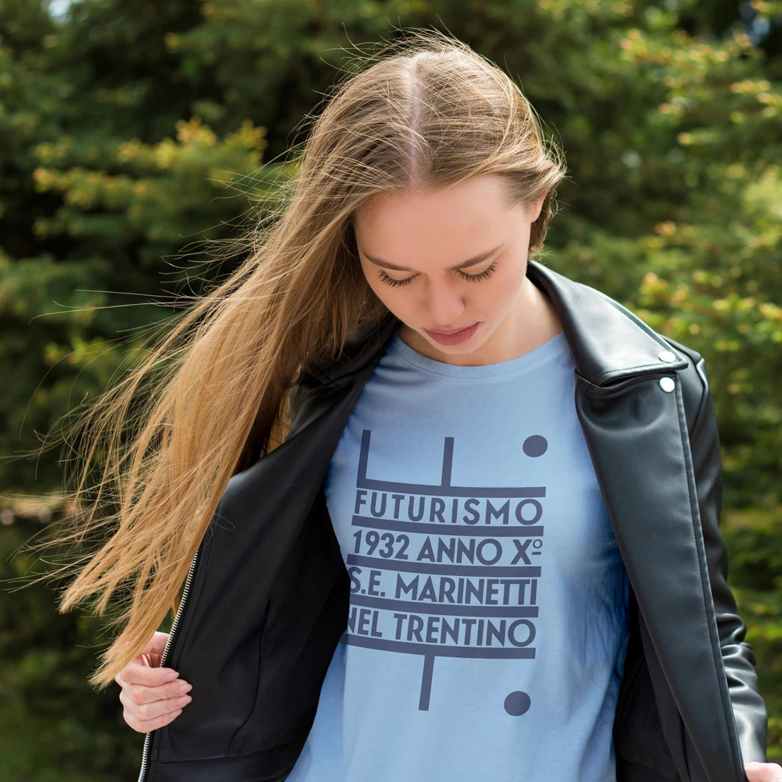 Woman  wearing a blue t-shirt with 'Futurismo 1932 Marinetti' text and a black jacket outdoors