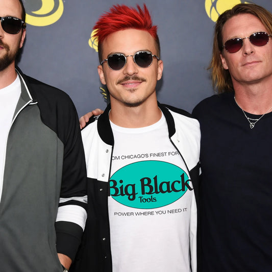 Three men standing together with one wearing a 'Big Black Tools' shirt against a gray background.