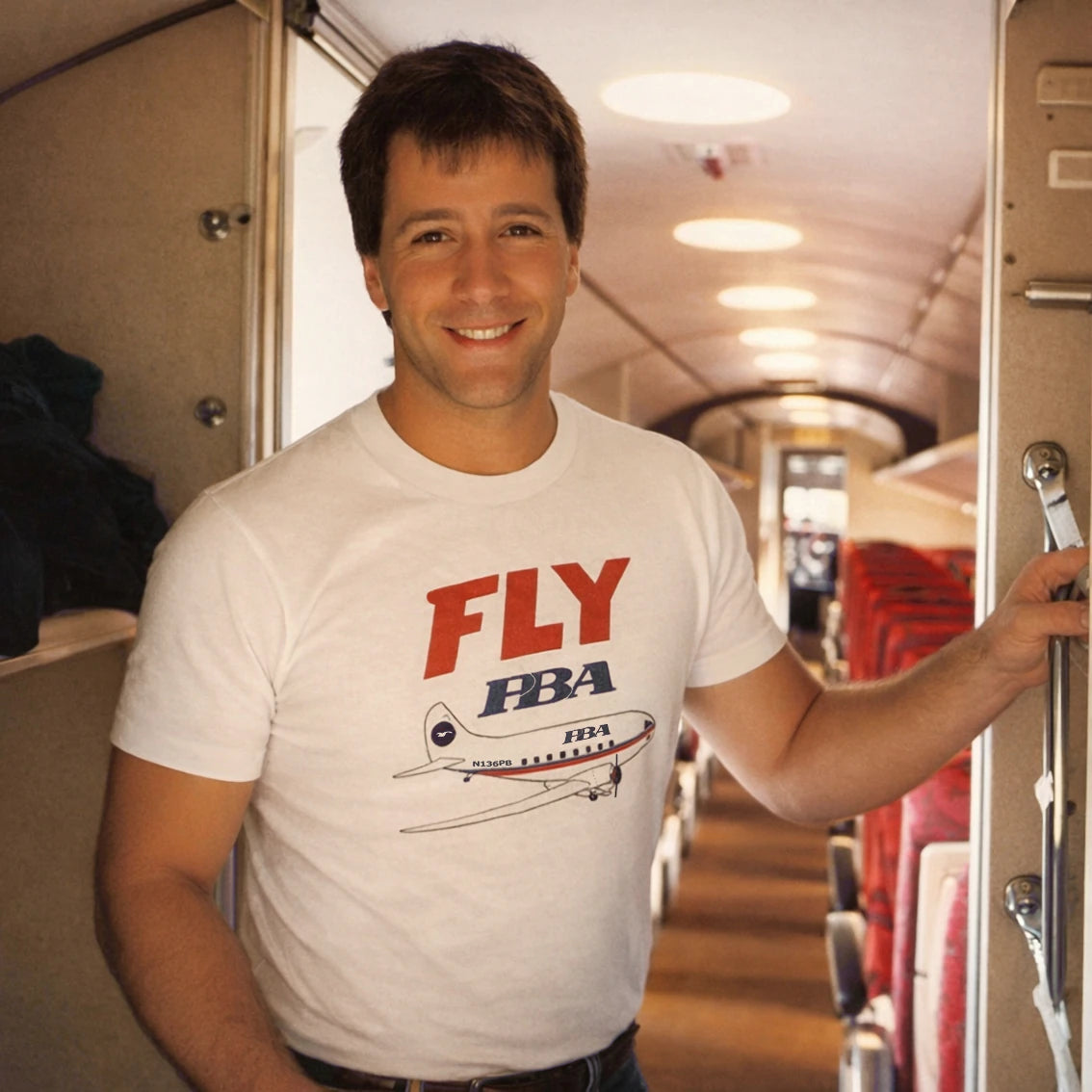 Man wearing a 'FLY HBA' t-shirt inside an airplane.