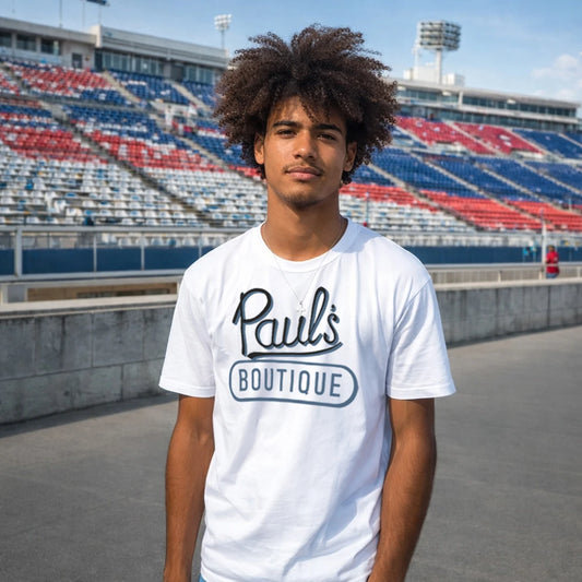 Man wearing a white t-shirt with 'Paul's Boutique' logo in an outdoor stadium setting