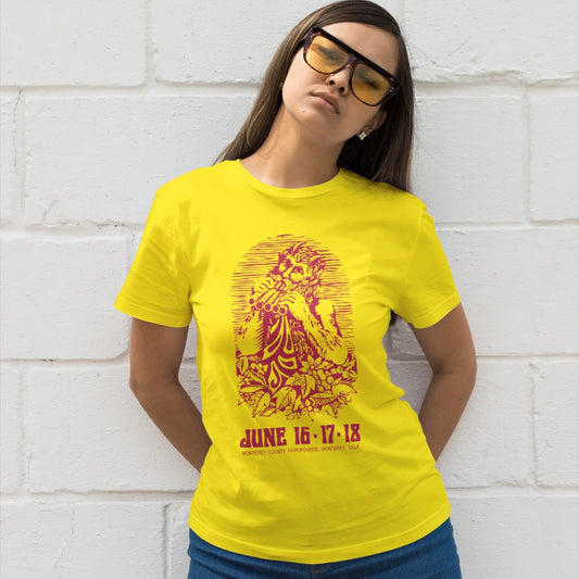 Woman wearing a yellow t-shirt with a red graphic design of Monterey Festival against a white brick wall.