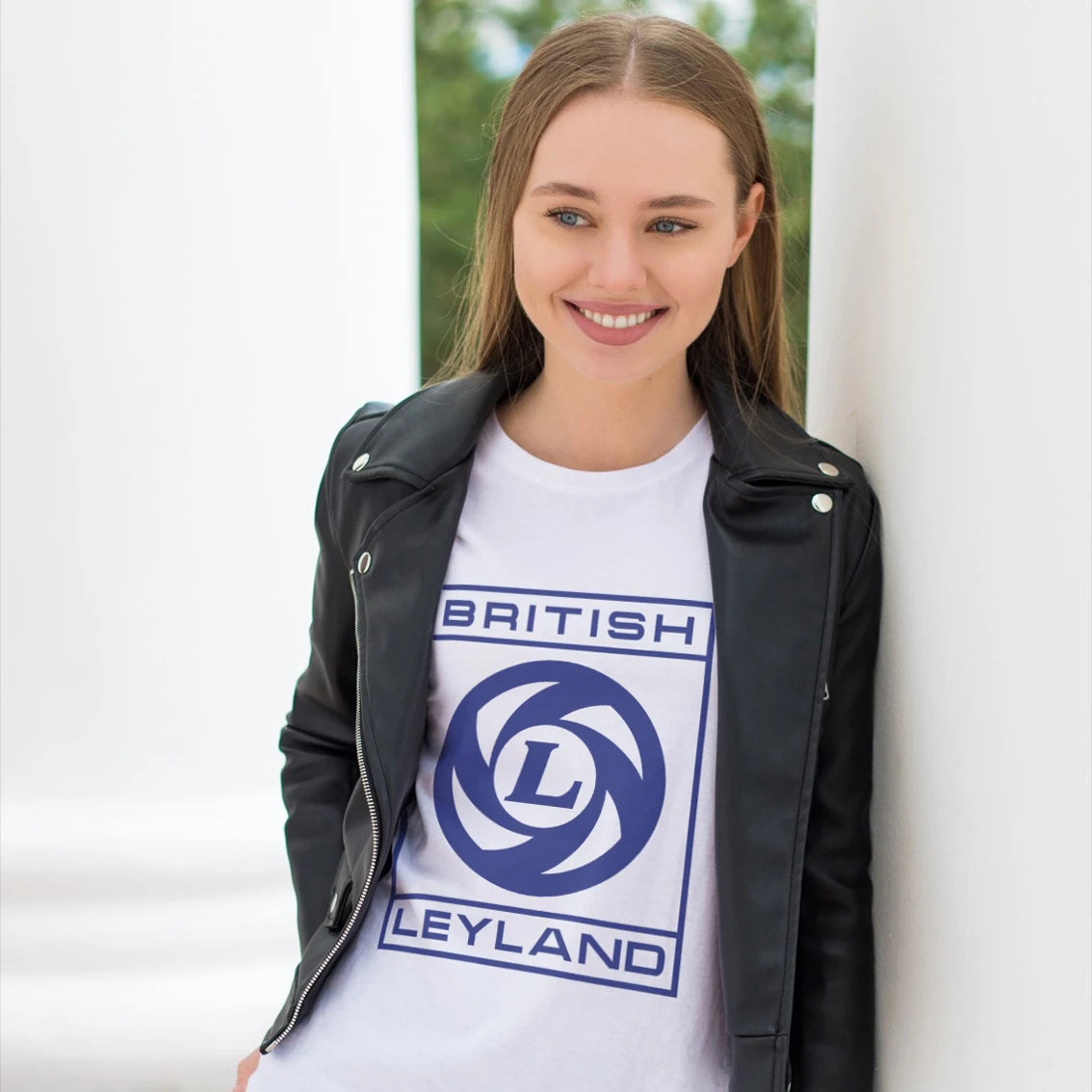 Woman wearing a white t-shirt with 'British Leyland' logo and text, standing outdoors.