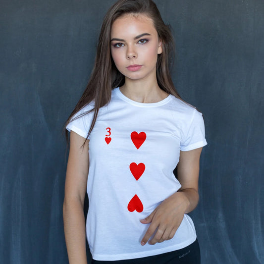 A woman is wearing a white t-shirt with 'Three of hearts' design on a dark background