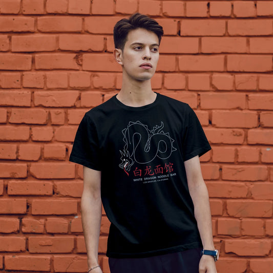 A man is wearing a black t-shirt with a graphic design of the dragon and 'WHITE DRAGON NOODLE BAR' text in front of a brick wall
